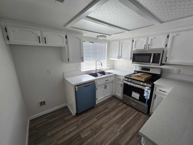 kitchen with a sink, appliances with stainless steel finishes, dark wood-style flooring, and white cabinetry