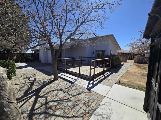 back of house with stucco siding, a patio, a fenced backyard, and a deck