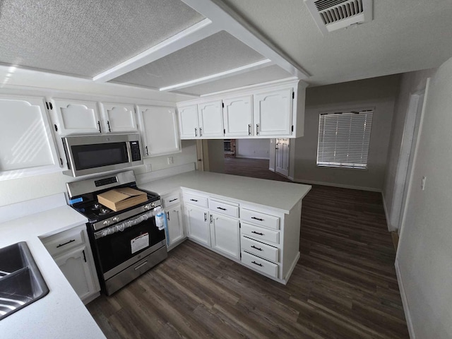 kitchen with visible vents, a peninsula, stainless steel appliances, white cabinetry, and dark wood-style flooring