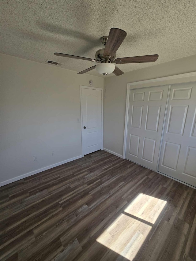 unfurnished bedroom with visible vents, baseboards, a closet, dark wood-style floors, and a ceiling fan