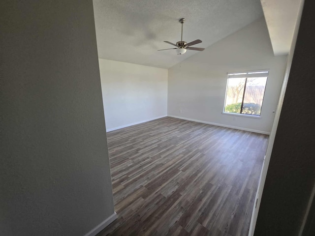 spare room with ceiling fan, baseboards, vaulted ceiling, dark wood-style floors, and a textured ceiling