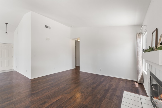 unfurnished living room with a fireplace, high vaulted ceiling, baseboards, wood finished floors, and visible vents