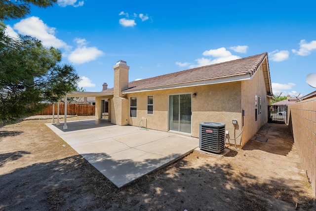 rear view of property featuring stucco siding, a fenced backyard, central AC, and a patio
