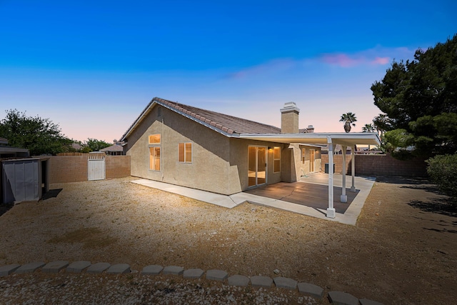 back of property featuring a fenced backyard, a patio area, stucco siding, and a chimney