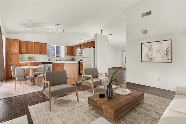 living room featuring visible vents, ceiling fan, vaulted ceiling, and light wood-type flooring