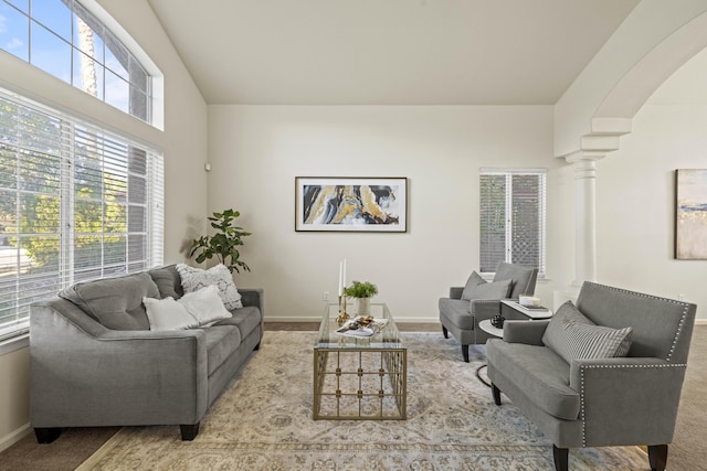 living room featuring lofted ceiling, decorative columns, and light carpet