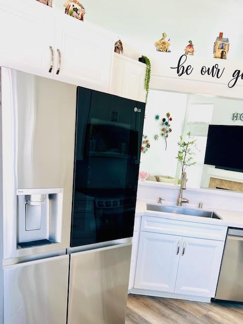 kitchen featuring a sink, appliances with stainless steel finishes, white cabinets, and light countertops