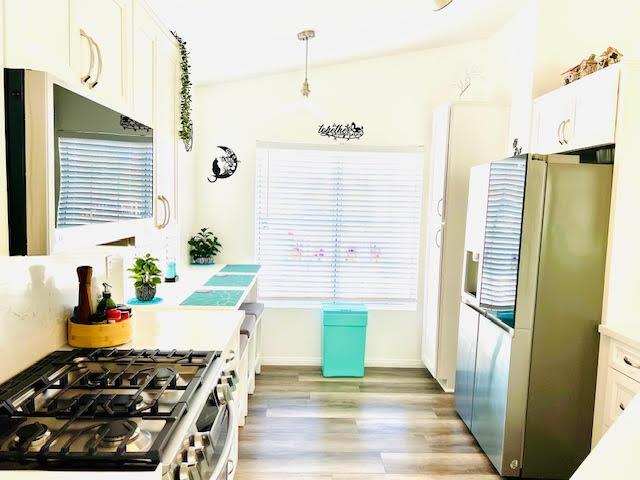 kitchen with stainless steel appliances, light wood finished floors, light countertops, and white cabinetry