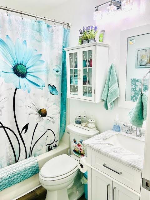 bathroom featuring toilet, shower / tub combo with curtain, and vanity