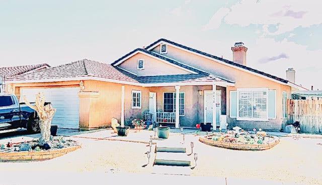 view of front of home with a garage, stucco siding, a chimney, and fence