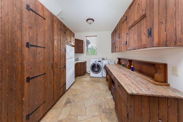 washroom featuring stone finish floor, laundry area, washer and dryer, and a sink