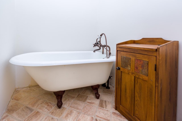 bathroom featuring stone finish floor and a freestanding tub