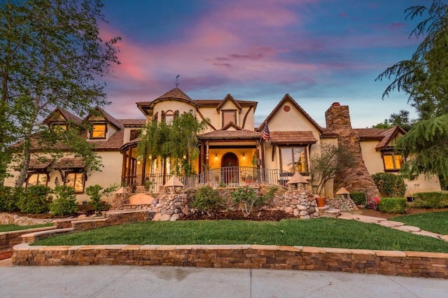 view of front of house featuring stucco siding, a chimney, and a front yard