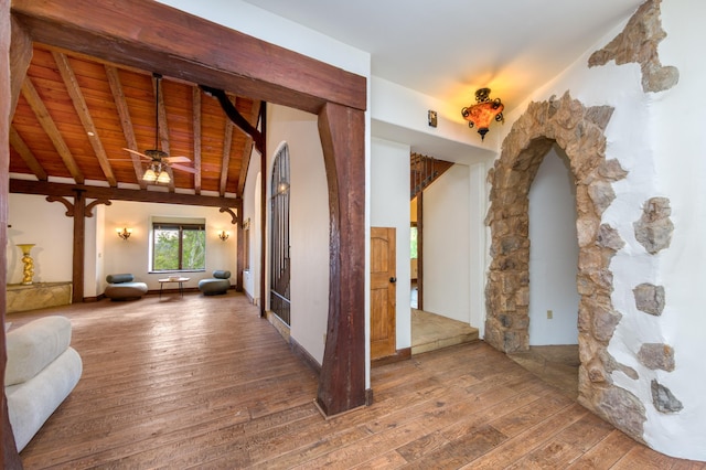 hallway featuring wood-type flooring, arched walkways, beamed ceiling, and wooden ceiling