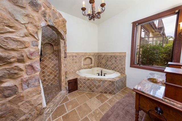 full bath with a garden tub, stone tile floors, vanity, an inviting chandelier, and tiled shower