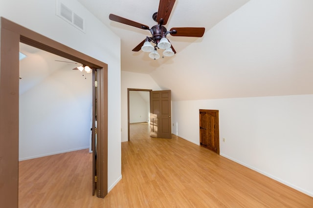additional living space with light wood-style flooring, ceiling fan, baseboards, lofted ceiling, and visible vents