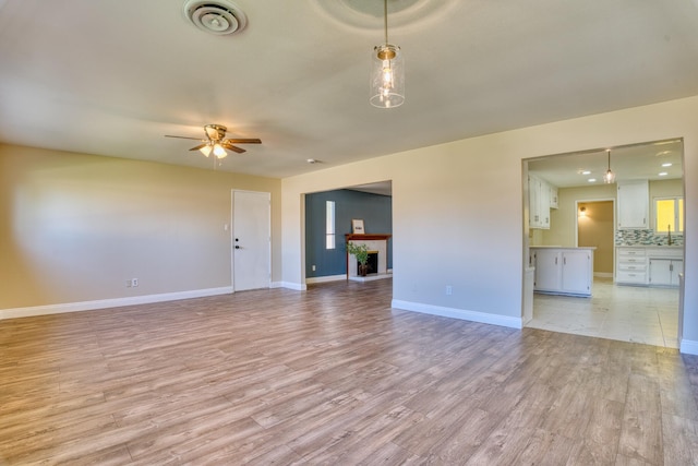45209 Lorimer Ave, Lancaster, CA 93534 - unfurnished living room featuring light wood finished floors, ceiling fan, baseboards, and a fireplace with raised hearth