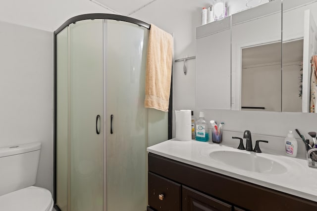 bathroom featuring toilet, a shower with door, and vanity