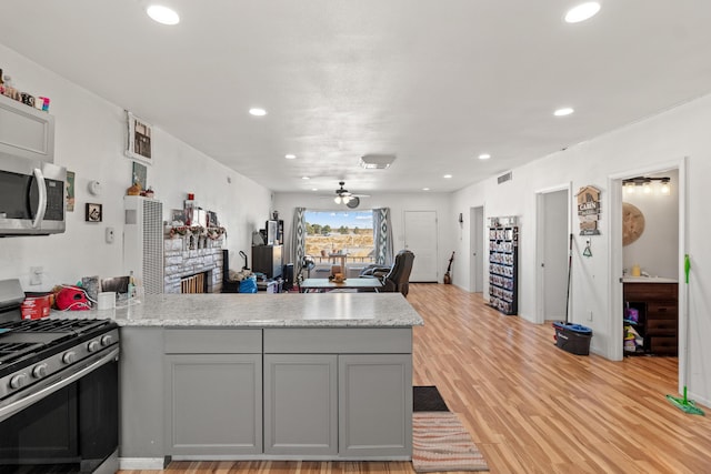 kitchen with appliances with stainless steel finishes, gray cabinets, ceiling fan, and kitchen peninsula