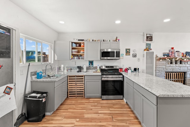 kitchen with sink, stainless steel appliances, gray cabinetry, and kitchen peninsula