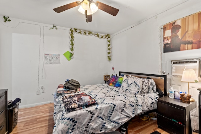 bedroom with ceiling fan, a wall mounted AC, and light hardwood / wood-style flooring