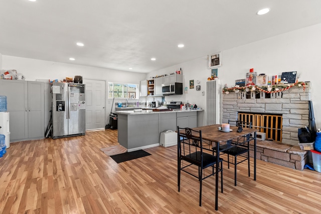 dining area with light hardwood / wood-style flooring and a stone fireplace