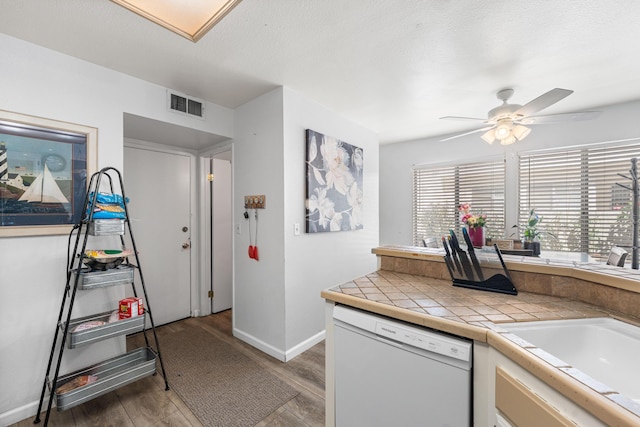 37940 E 42nd St Apt 115, Palmdale, CA 93552 - kitchen with white dishwasher, a ceiling fan, tile counters, wood finished floors, and baseboards