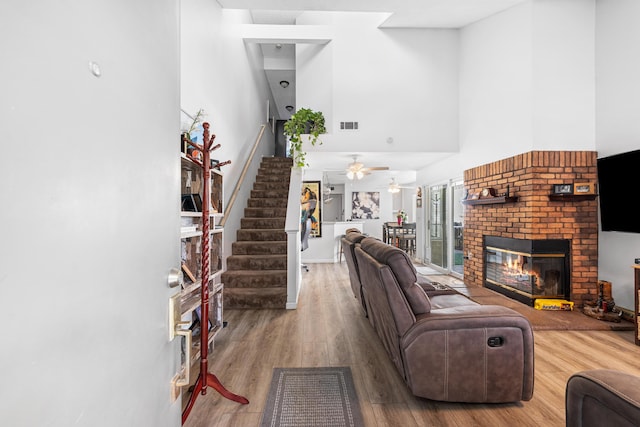 37940 E 42nd St Apt 115, Palmdale, CA 93552 - living area featuring stairway, a towering ceiling, a brick fireplace, wood finished floors, and ceiling fan