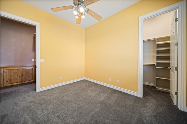 unfurnished bedroom featuring a walk in closet, ceiling fan, a closet, and dark carpet