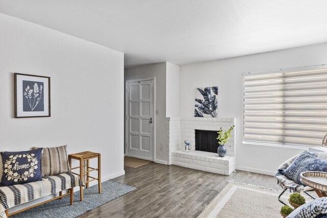 living room featuring hardwood / wood-style flooring and a brick fireplace