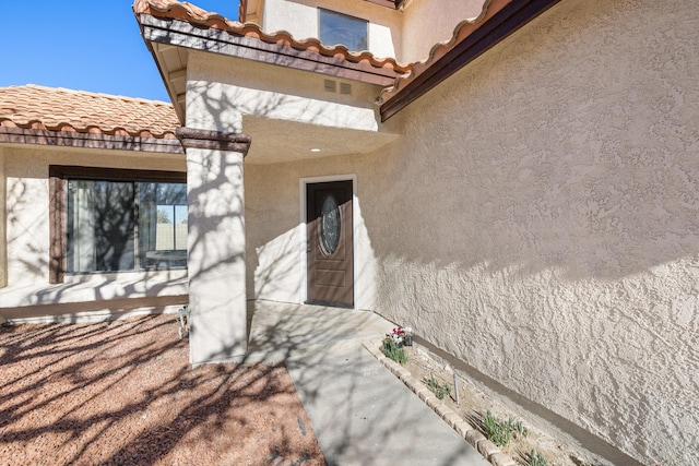 doorway to property with a tile roof and stucco siding