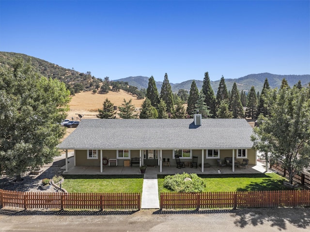 ranch-style home with a mountain view, a patio area, and a front yard