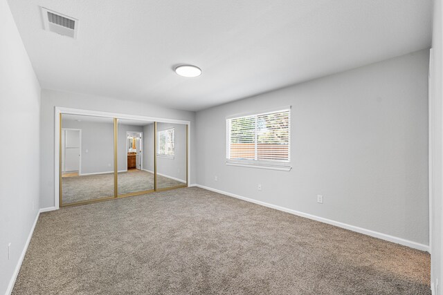 unfurnished bedroom featuring carpet flooring, baseboards, visible vents, and a closet