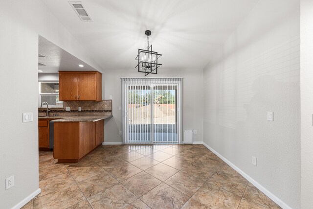 kitchen featuring a sink, a chandelier, brown cabinetry, tasteful backsplash, and visible vents