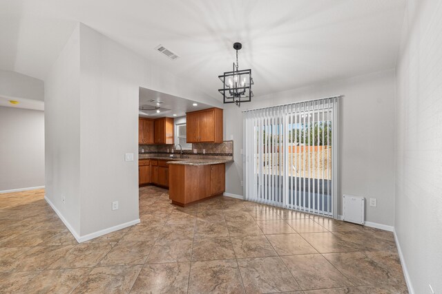 kitchen featuring visible vents, brown cabinets, a sink, baseboards, and a chandelier