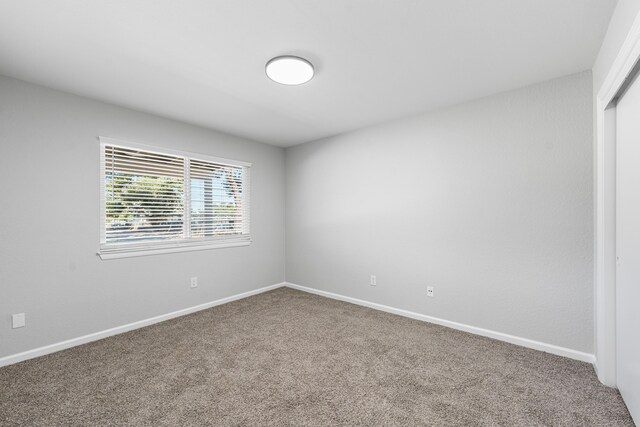 carpeted empty room with baseboards