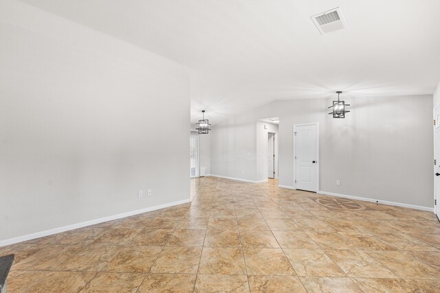 spare room with baseboards, visible vents, lofted ceiling, and a chandelier