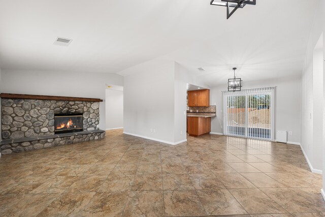 unfurnished living room featuring baseboards, visible vents, an inviting chandelier, and a fireplace