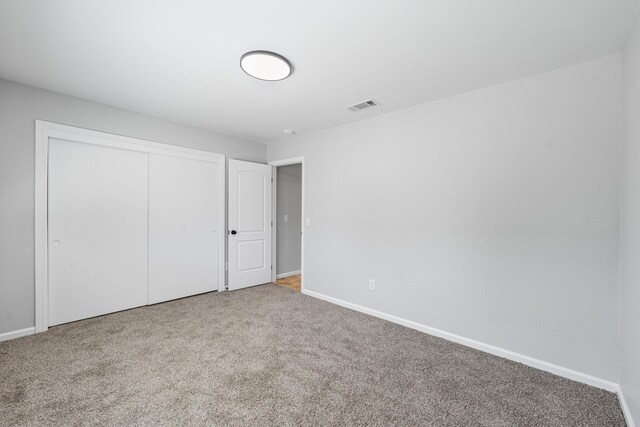 unfurnished bedroom featuring baseboards, carpet, a closet, and visible vents