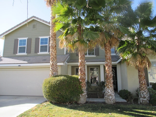 view of front facade featuring driveway, an attached garage, a tile roof, and stucco siding