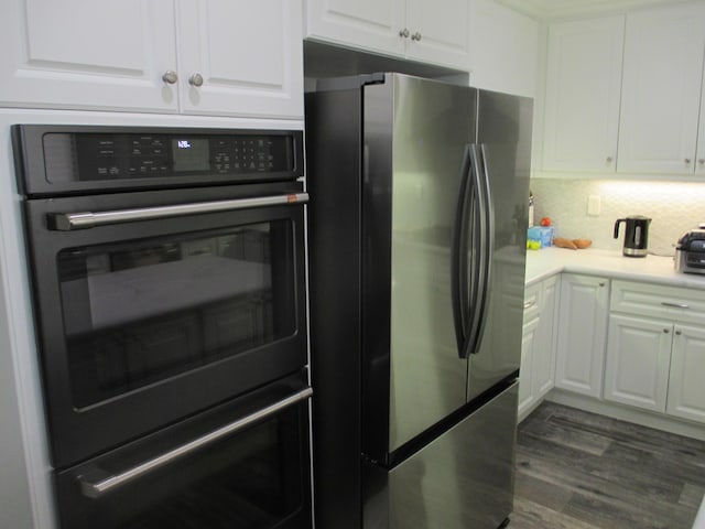 kitchen with freestanding refrigerator, white cabinets, and dobule oven black