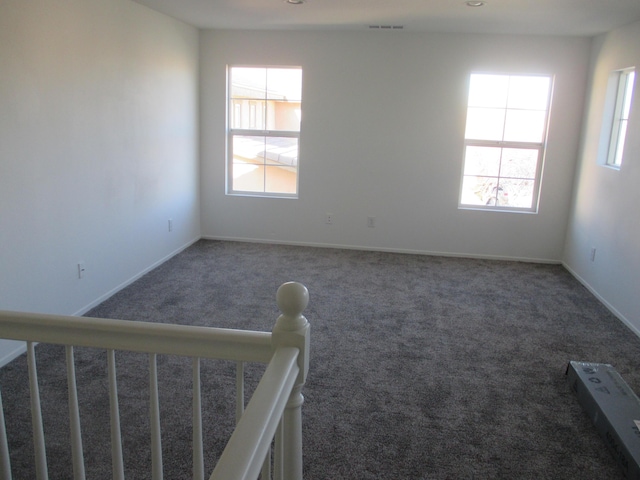 empty room featuring stairway, carpet flooring, visible vents, and baseboards