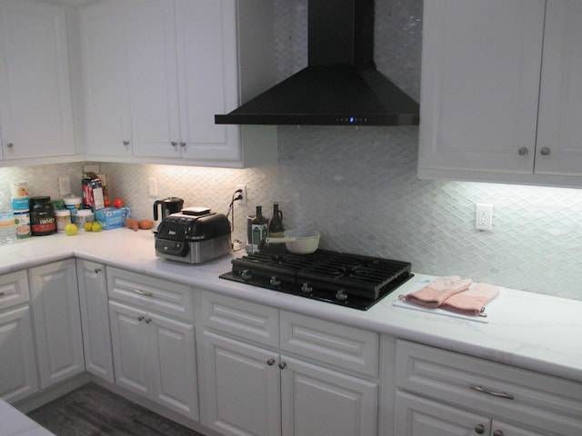 kitchen featuring black gas cooktop, white cabinets, light countertops, and wall chimney exhaust hood