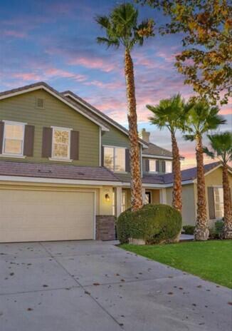 traditional-style home with a garage, driveway, and a front lawn