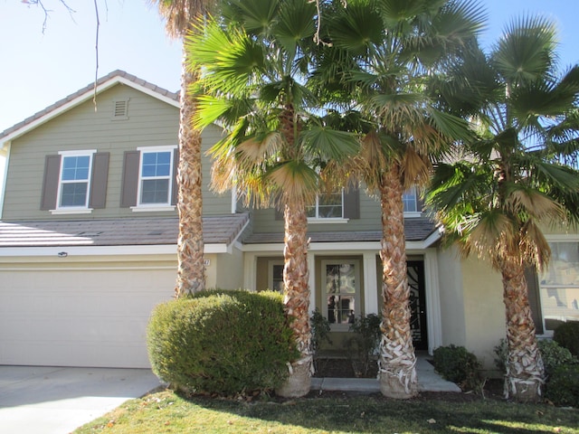 view of front of property with concrete driveway, an attached garage, and stucco siding