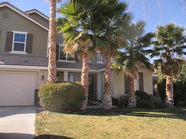 view of front of property with concrete driveway, an attached garage, a front lawn, and stucco siding