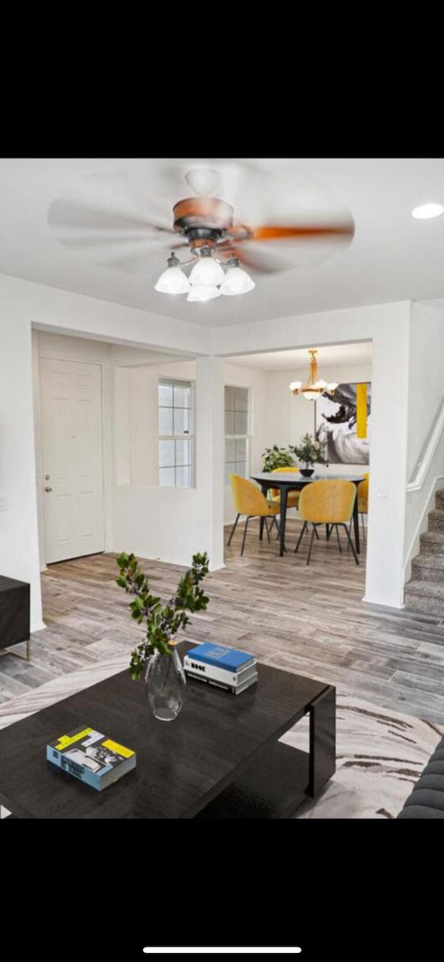 dining area featuring wood finished floors, ceiling fan, and stairs