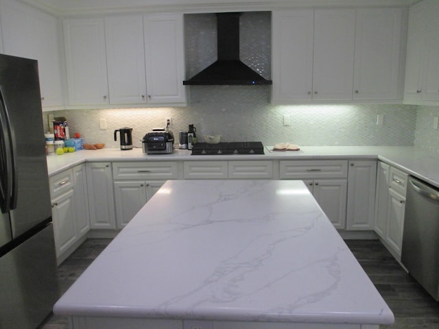 kitchen featuring black cooktop, stainless steel dishwasher, freestanding refrigerator, white cabinets, and wall chimney range hood