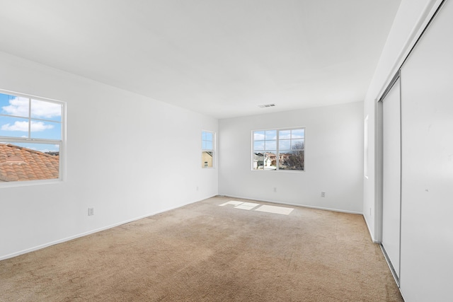 unfurnished bedroom with light colored carpet and a closet