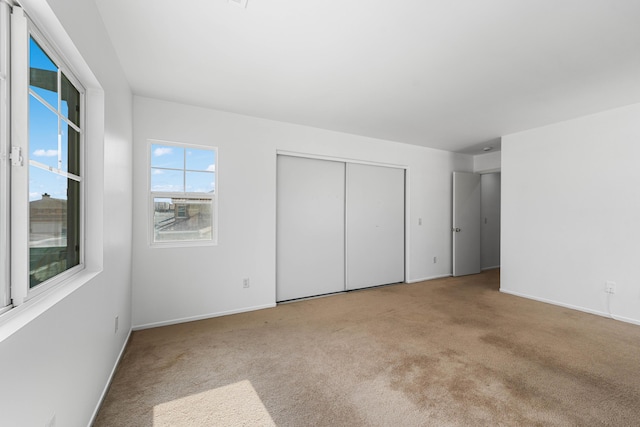 unfurnished bedroom with light carpet and a closet